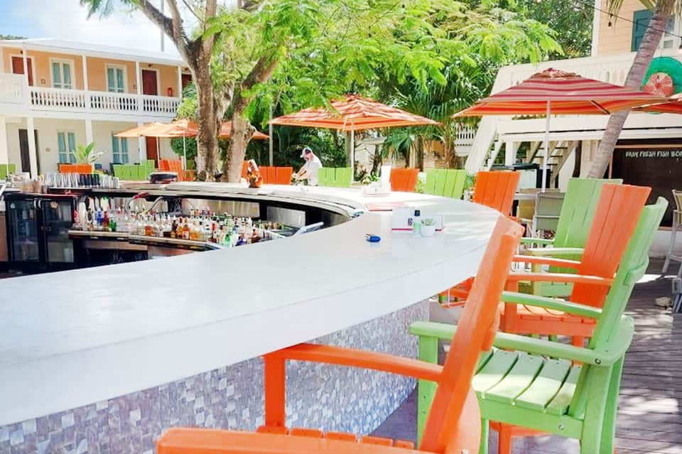 Outdoor bar area with colorful umbrellas, white counter, and tropical landscaping
