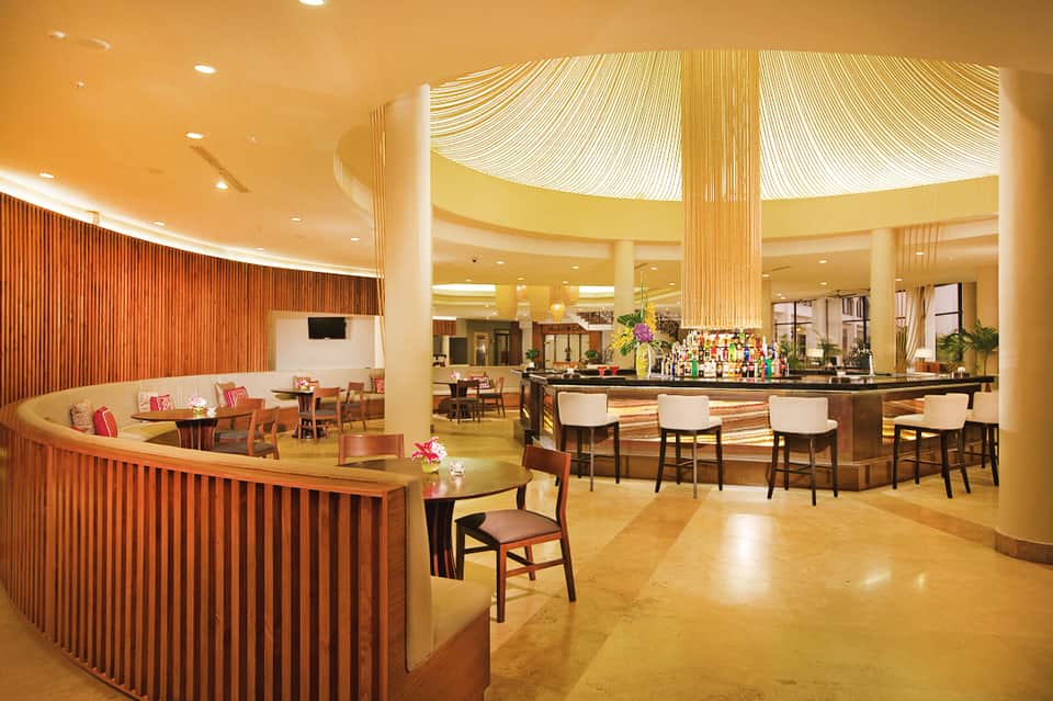 Modern hotel bar and lounge area with warm wood accents, ambient lighting, and comfortable seating