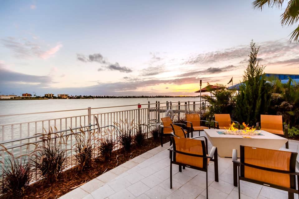 Waterfront fire pit seating area at sunset with lake views and palm trees