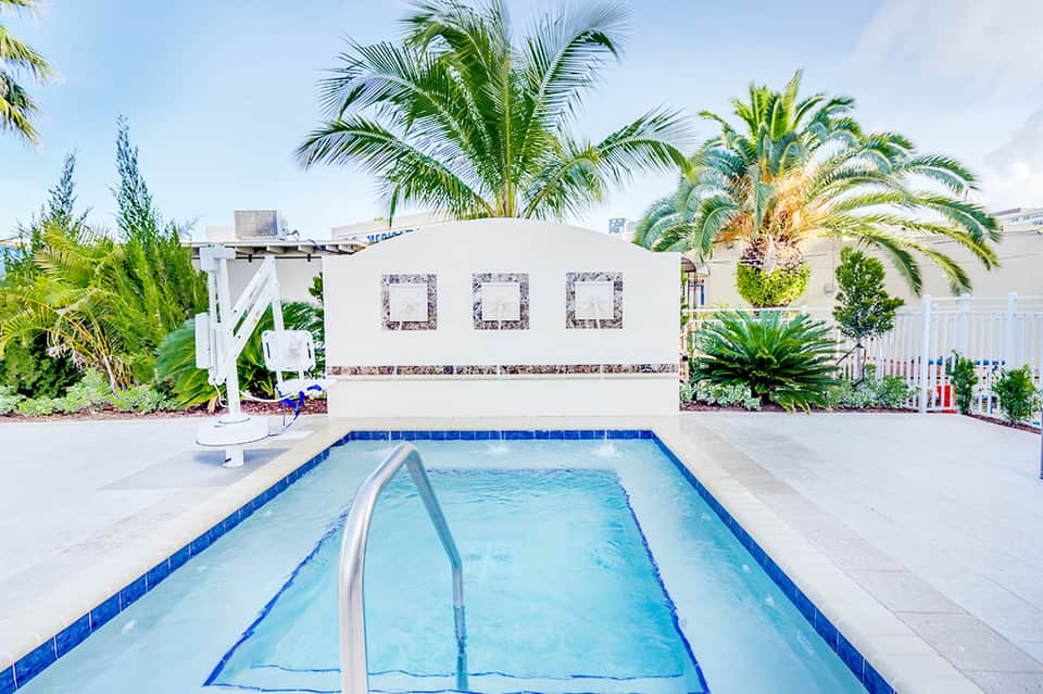 Rectangular swimming pool with palm trees and white cabana structure in tropical resort setting