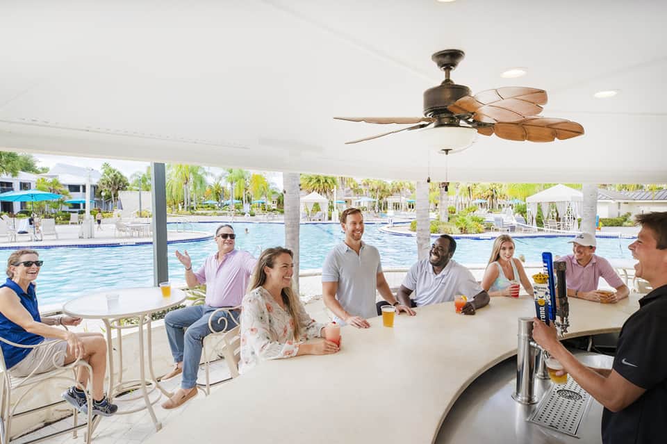 Indoor covered bar area with patrons enjoying drinks beside large resort pool