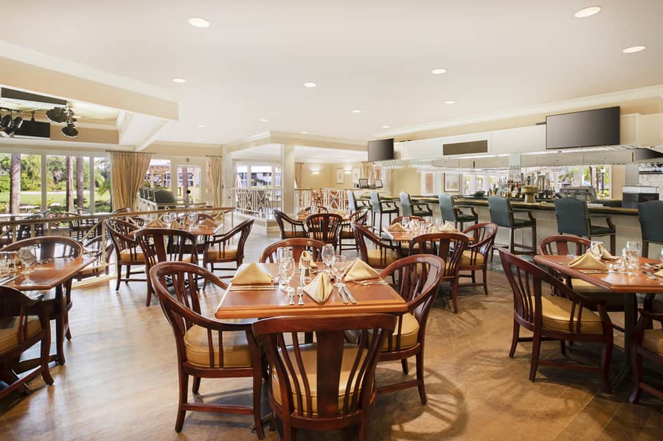 Elegant dining room with round wooden tables, chairs, and expansive windows