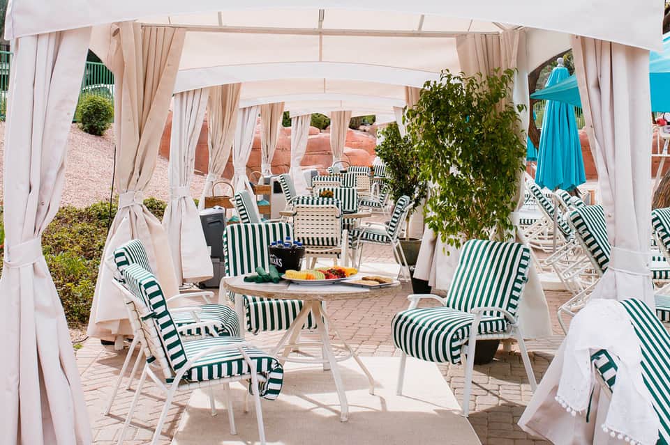 Upscale outdoor dining cabanas with white curtains and green striped lounge chairs