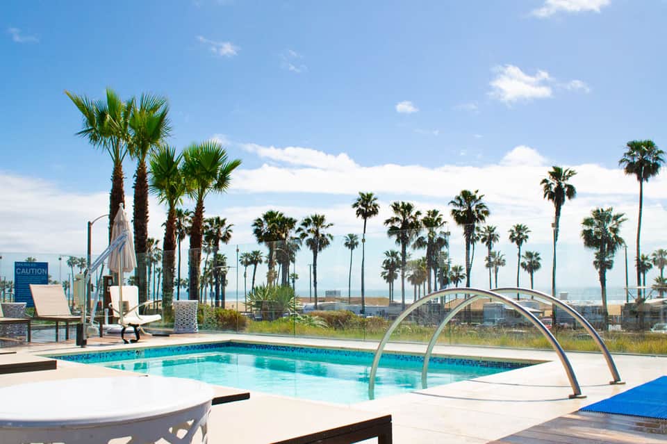 Resort pool with palm trees and ocean view, featuring lounge chairs and metal archway
