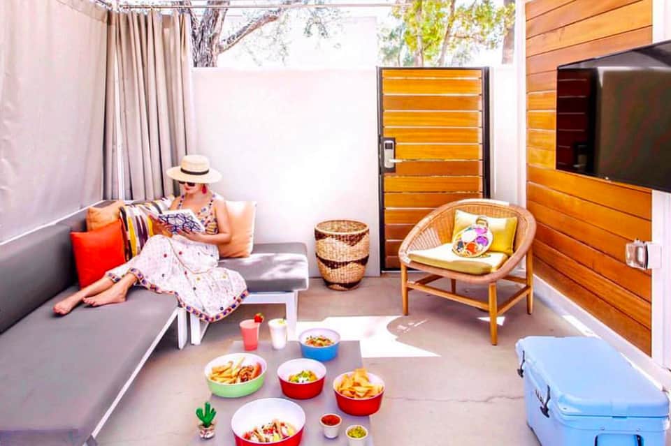 Colorful rooftop terrace with gray seating, wooden doors, and spread of international cuisine