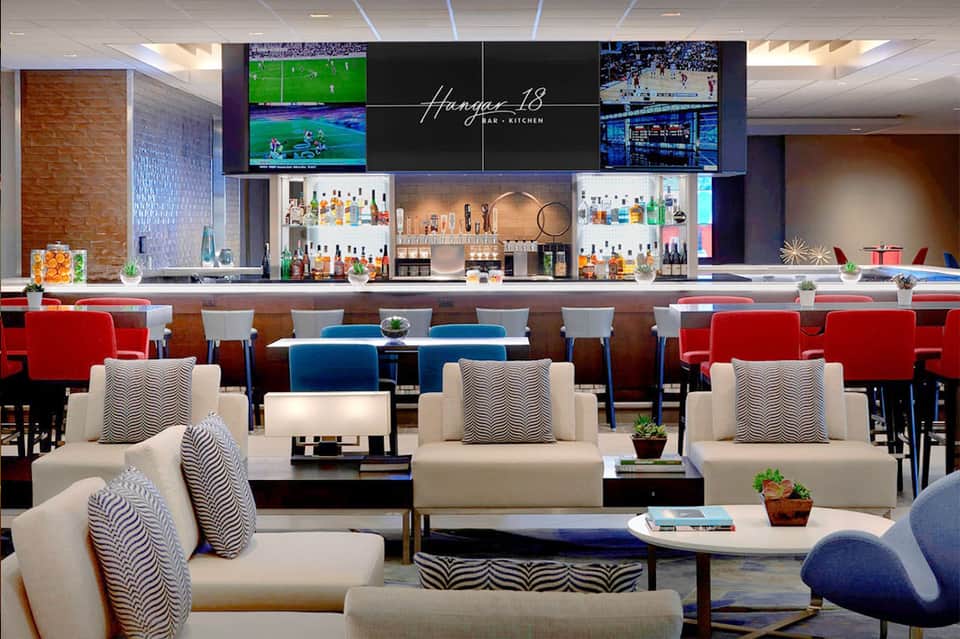 Modern bar and lounge with colorful seating and multiple TV screens