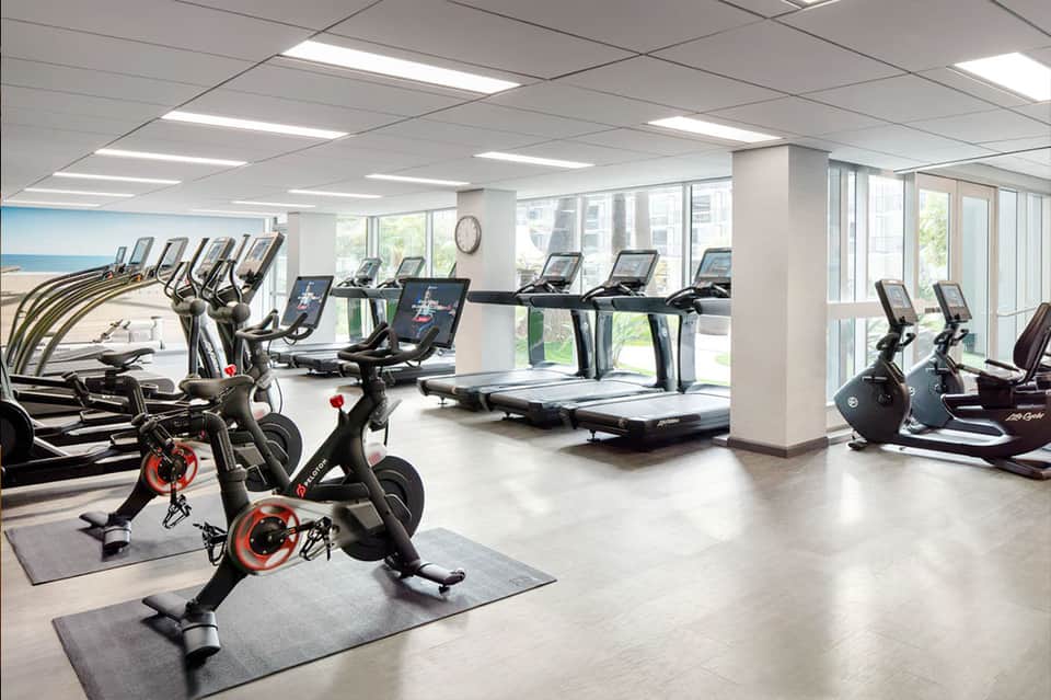 Modern hotel fitness center with cardio equipment, stationary bikes, treadmills, and large windows