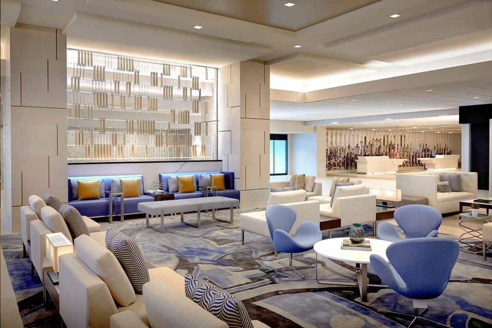 Modern hotel lobby lounge with blue and cream seating, geometric patterns, and wine bar
