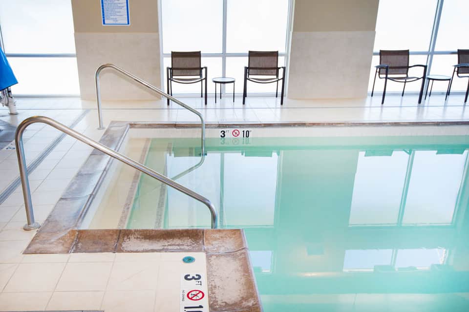 Indoor swimming pool with depth markers and metal railings in a bright, modern facility