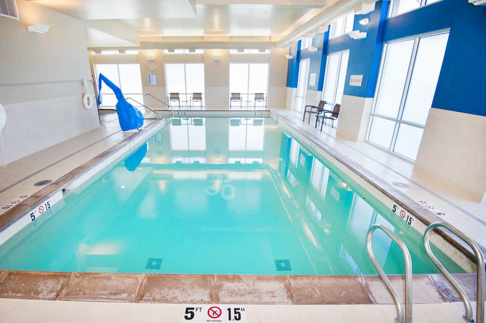 Indoor lap pool with turquoise water, blue walls, and large windows in a bright facility