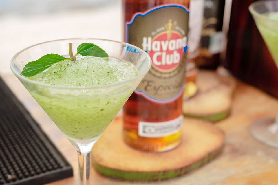 Green mojito cocktail with Havana Club rum bottle in tropical setting