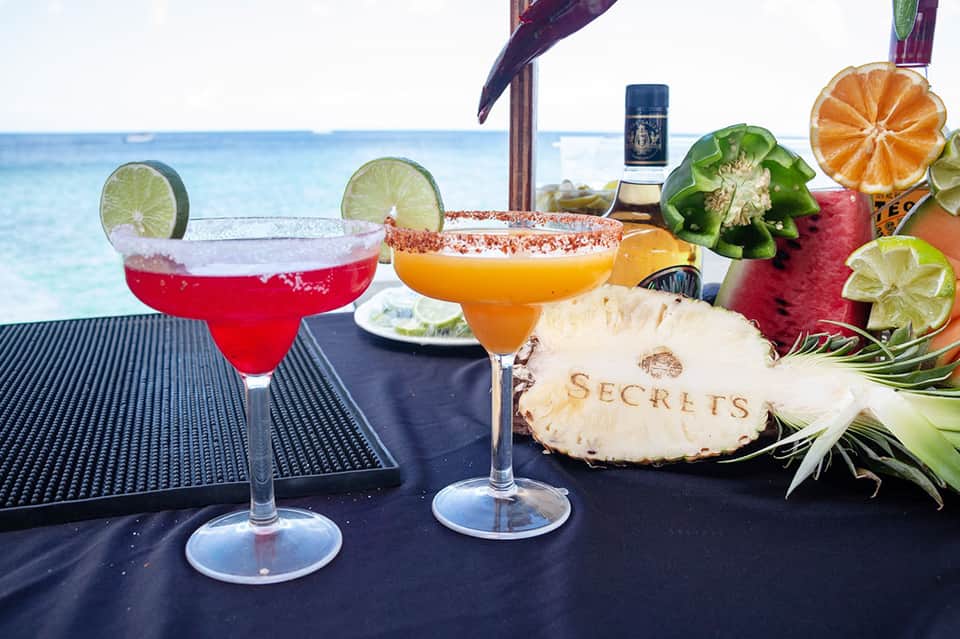 Tropical cocktails with salt rims and fresh citrus on oceanside bar table with pineapple
