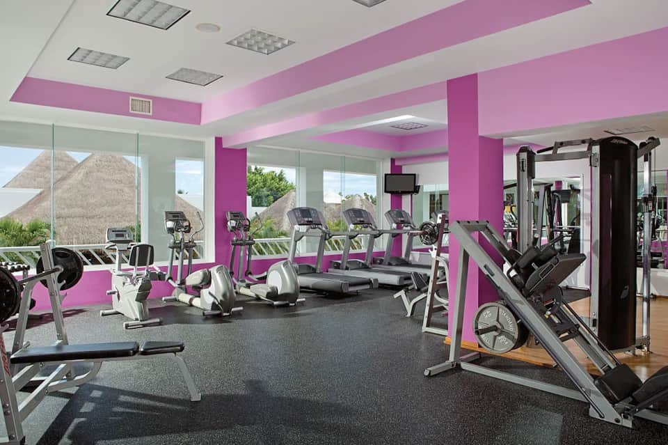 Modern fitness center with pink and white design, treadmills and exercise equipment