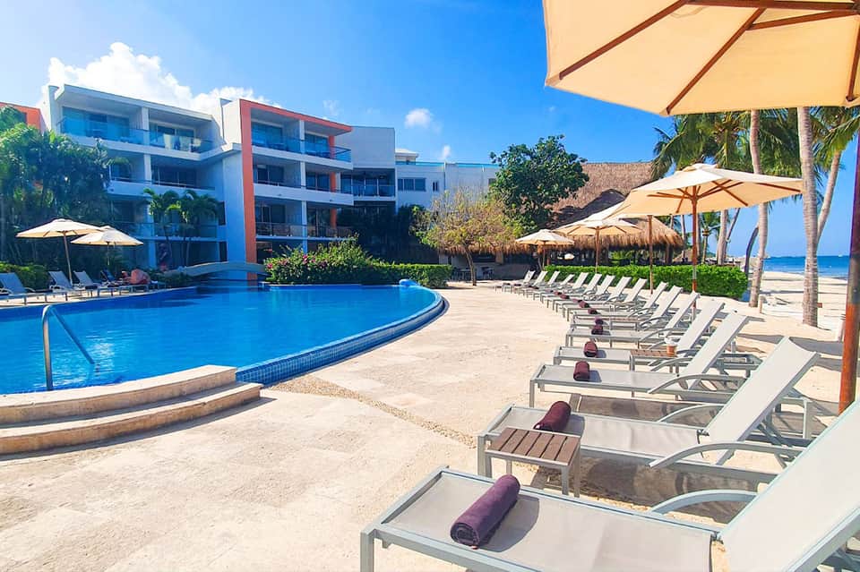 Resort curved pool with yellow umbrellas, lounge chairs, and beachfront beyond
