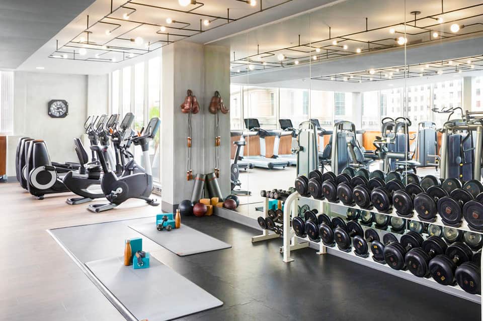 Modern fitness center with cardio equipment, weight racks, and exercise mats