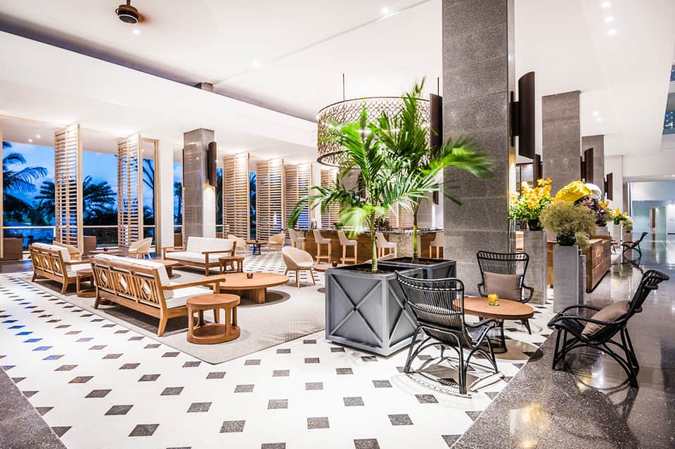 Luxury hotel lobby with modern furnishings, plants, and ocean views