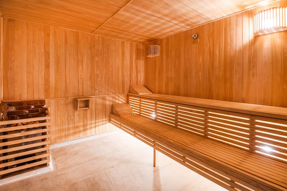 Empty wooden sauna interior with benches and warm cedar wood paneling