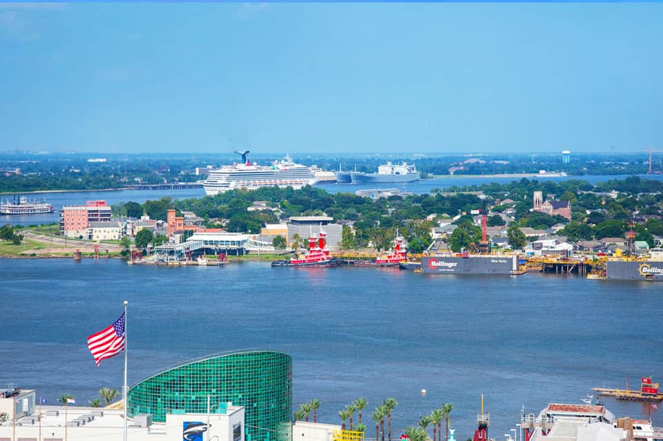 Aerial view of port city with cruise ship, waterfront buildings, and industrial dock facilities