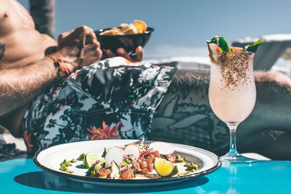 Gourmet ceviche dish with mojito cocktail served poolside overlooking ocean