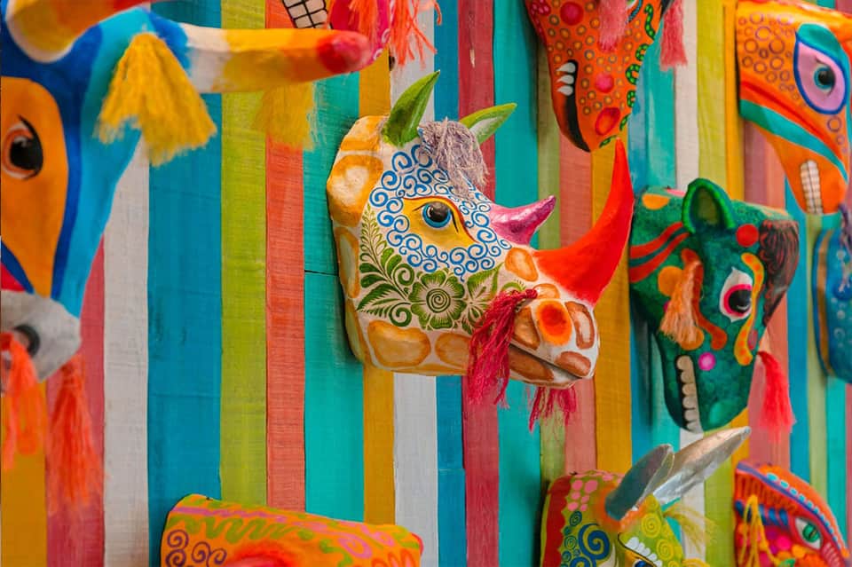 Colorful wooden carnival decorations featuring ornately painted animal heads with vibrant stripes