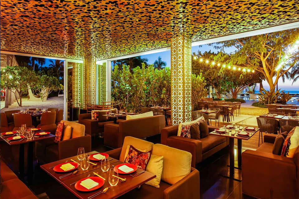 Upscale beachfront restaurant with orange accents, geometric ceiling, and ocean views