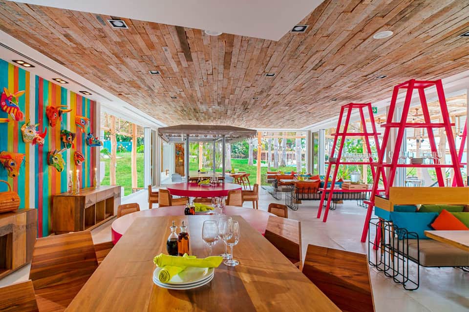 Contemporary dining space with wooden ceiling, colorful striped accent wall, and red sculptural elements