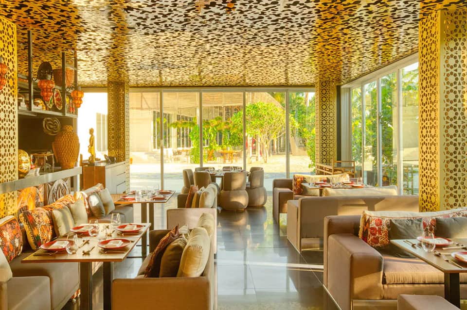 Upscale restaurant interior with gold-patterned walls, leather seating, and courtyard views