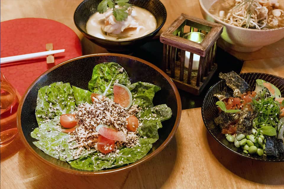Asian cuisine dishes including fresh salad with sesame seeds, dumpling soup, and noodle bowls