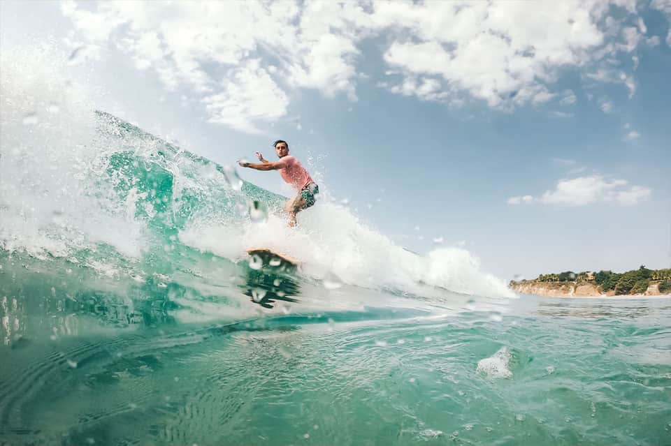 Surfer riding a wave in turquoise ocean water near sandy beach