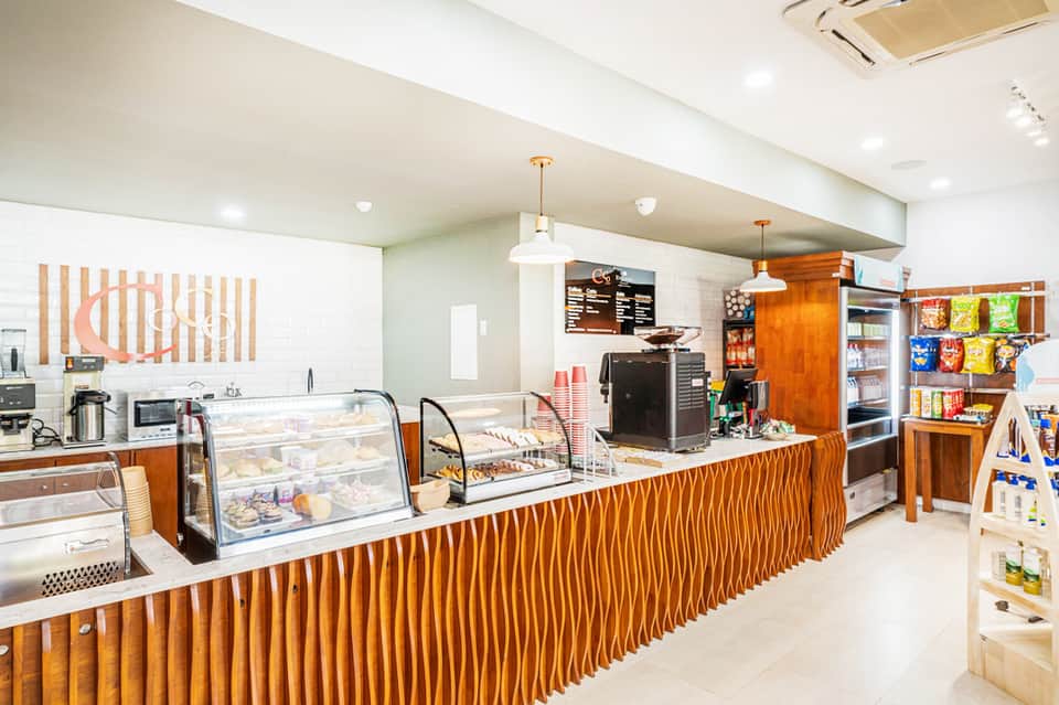 Modern resort café interior with wooden counter, display cases, and beverage station