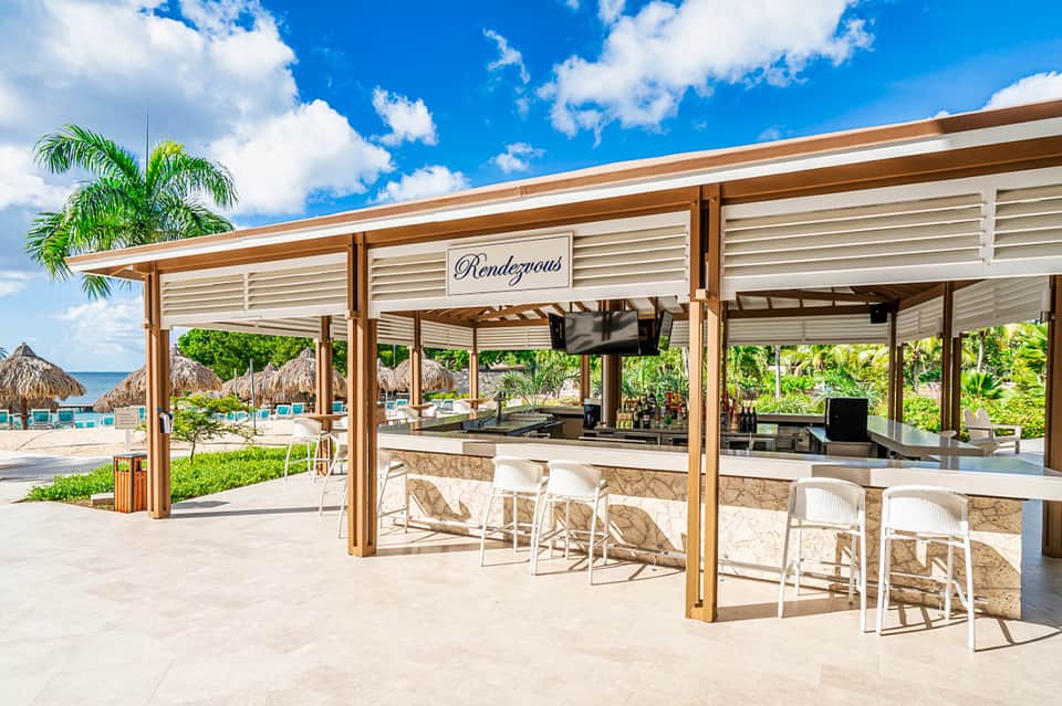 Beach bar with wooden pergola, thatched umbrellas, and ocean view at tropical resort