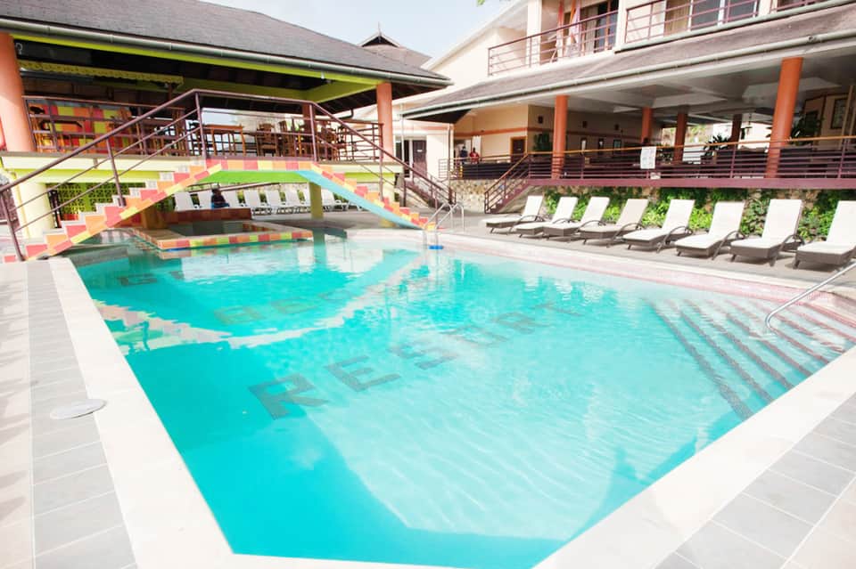Indoor lap pool with colorful bridge, lounge chairs, and modern resort architecture