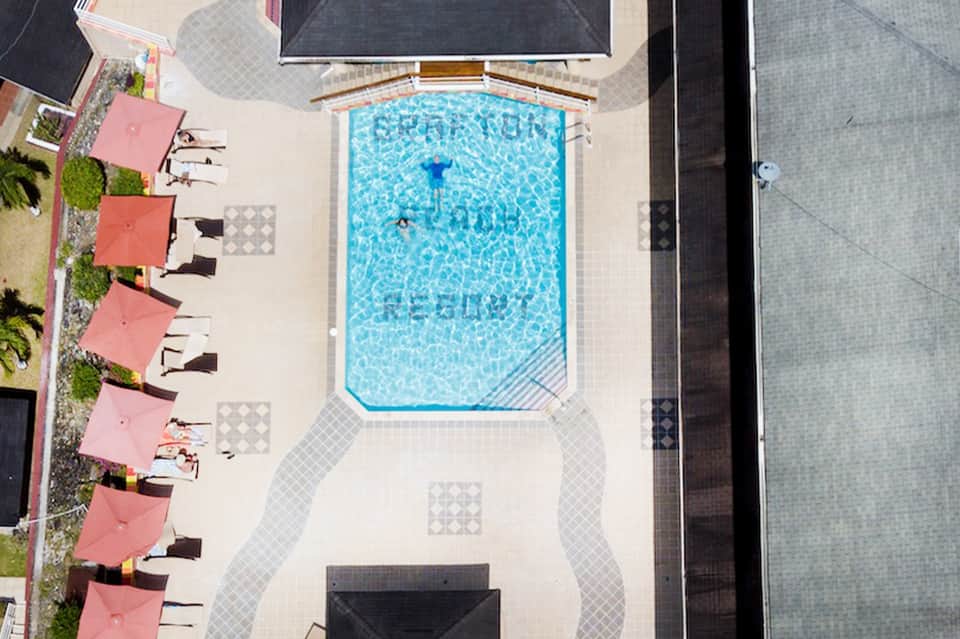 Aerial view of rectangular pool with red umbrellas and lounge chairs