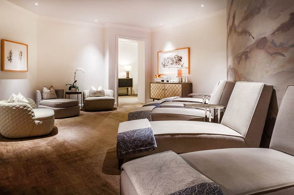 Luxury spa relaxation room with massage beds, lounge chairs, and neutral earth tones