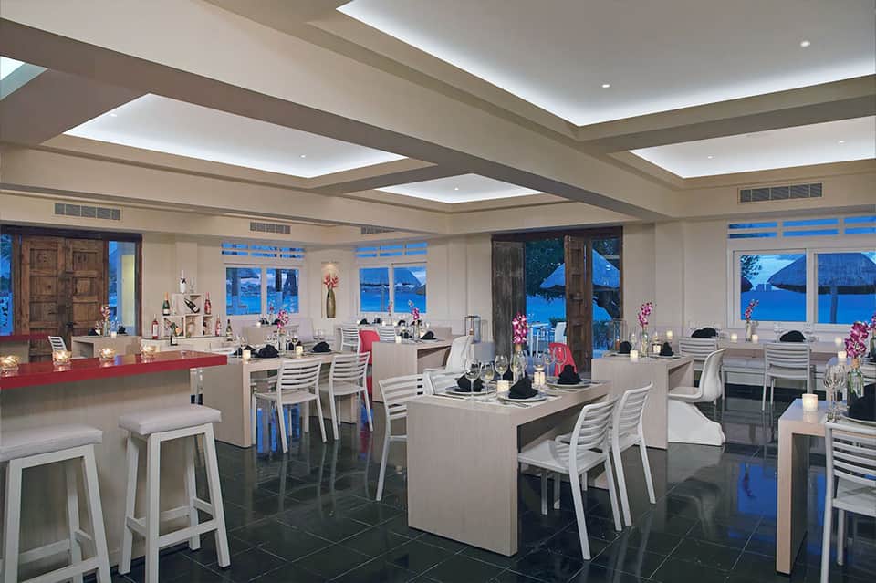 Modern seafront restaurant with floor-to-ceiling windows and ocean view at dusk