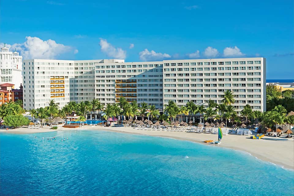Beachfront resort hotel with sand beach, turquoise water, and palm tree landscaping