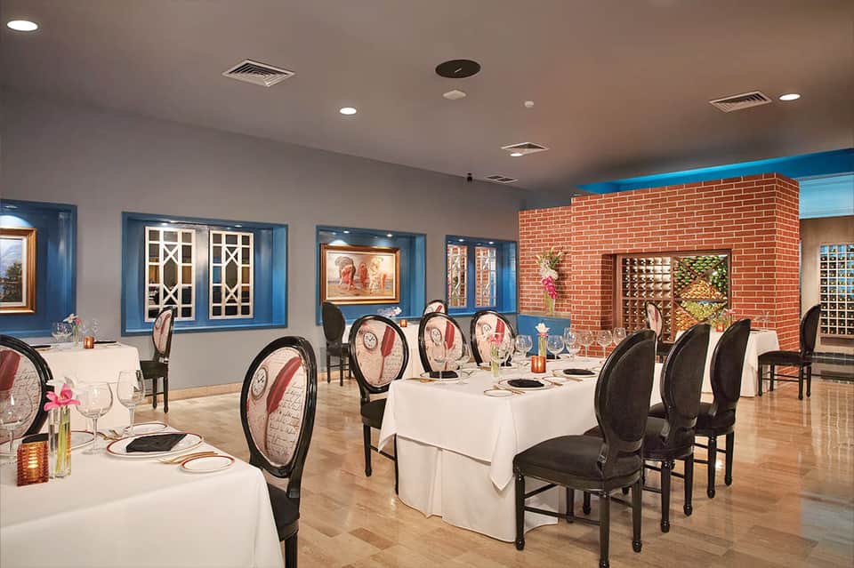 Elegant banquet room with round tables, blue trim, brick accent wall, and formal table settings