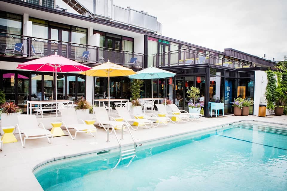 Resort pool area with colorful umbrellas, lounge chairs, and balcony building
