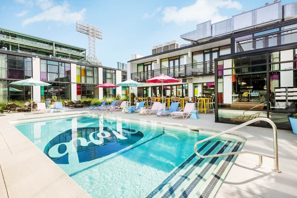 Modern hotel pool with colorful umbrellas, contemporary building, and lounge chairs