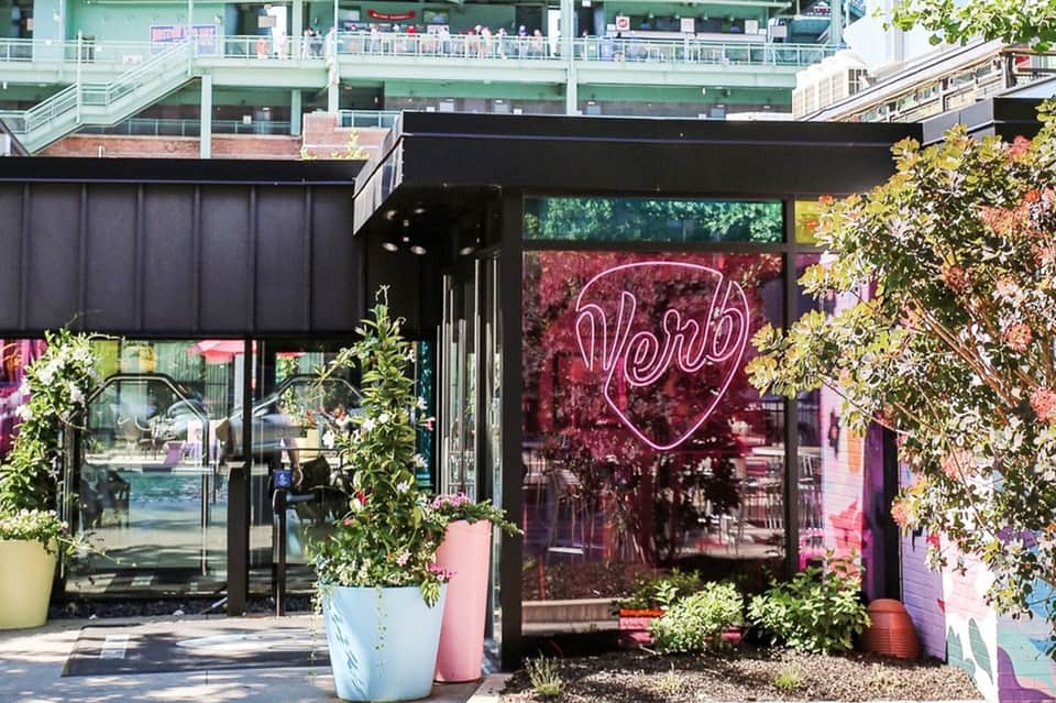 Modern restaurant entrance with neon heart sign and pink and yellow planters