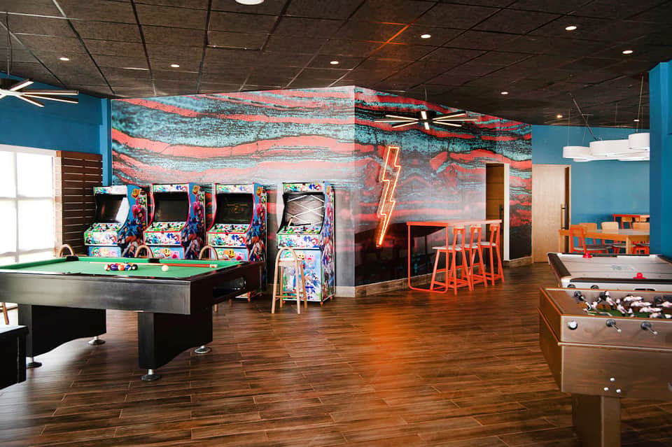 Game room with colorful arcade machines, pool table, and foosball table