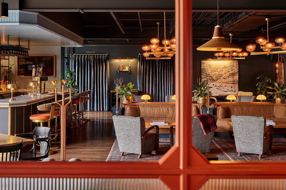 Modern resort lobby with copper pendant lights, wooden furniture, and contemporary decor