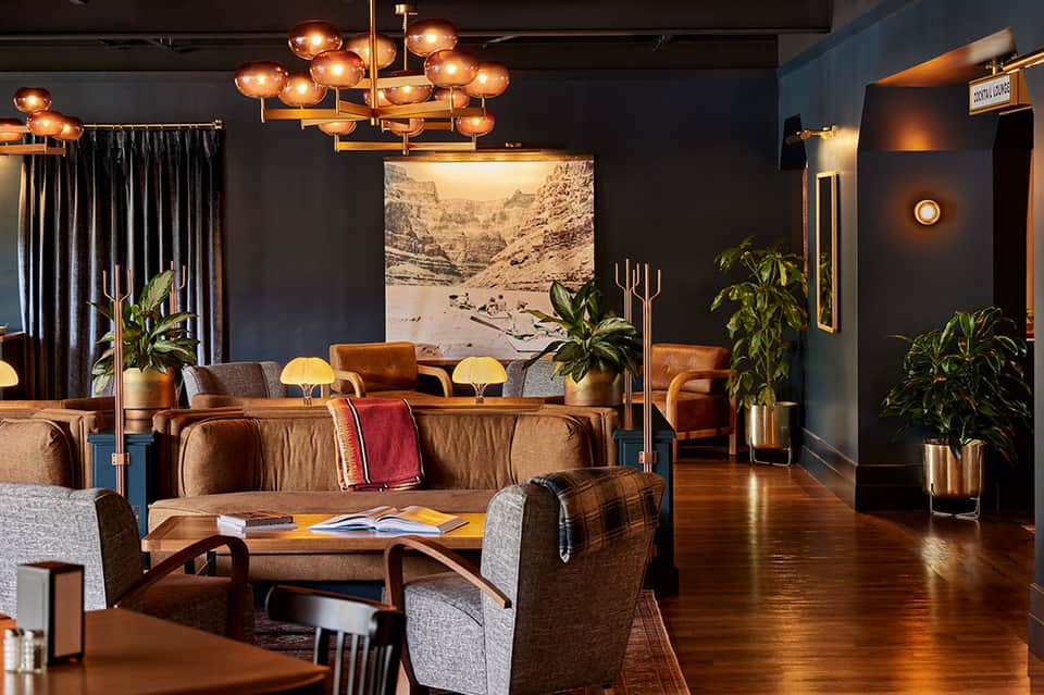 Contemporary hotel lounge with copper pendant lighting, leather seating, and artistic mountain photograph