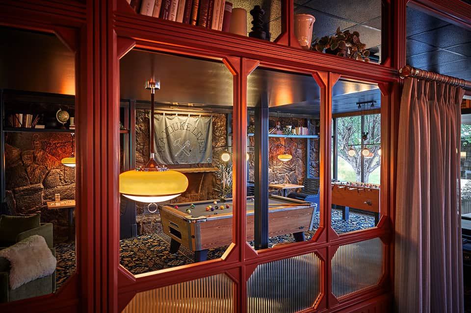 Game room interior with red wooden frames, pool table, and shelving with books and decor