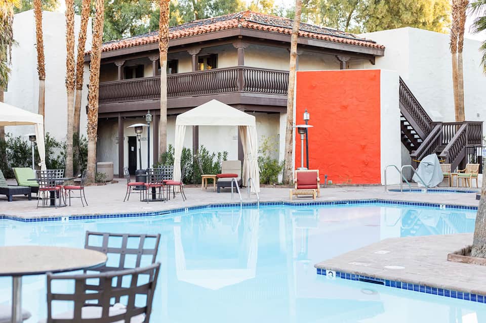 Resort pool with Spanish colonial architecture, palm trees, and lounge seating