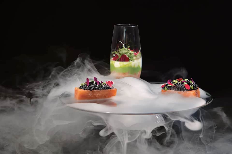 Fine dining plated dishes with microgreens and decorative smoke under glass dome