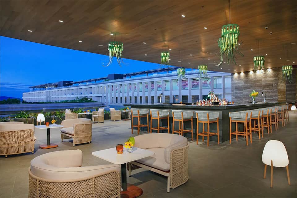 Modern waterfront bar and lounge area with hanging plants and contemporary seating