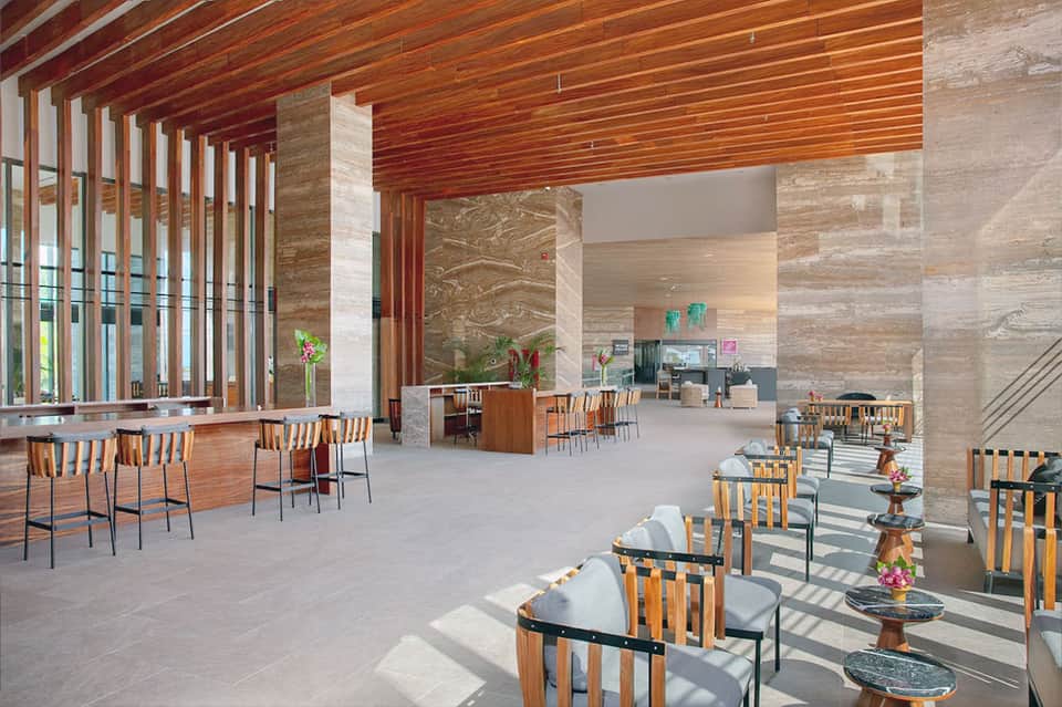 Contemporary lounge area with wooden ceiling, marble columns, and casual seating arrangements