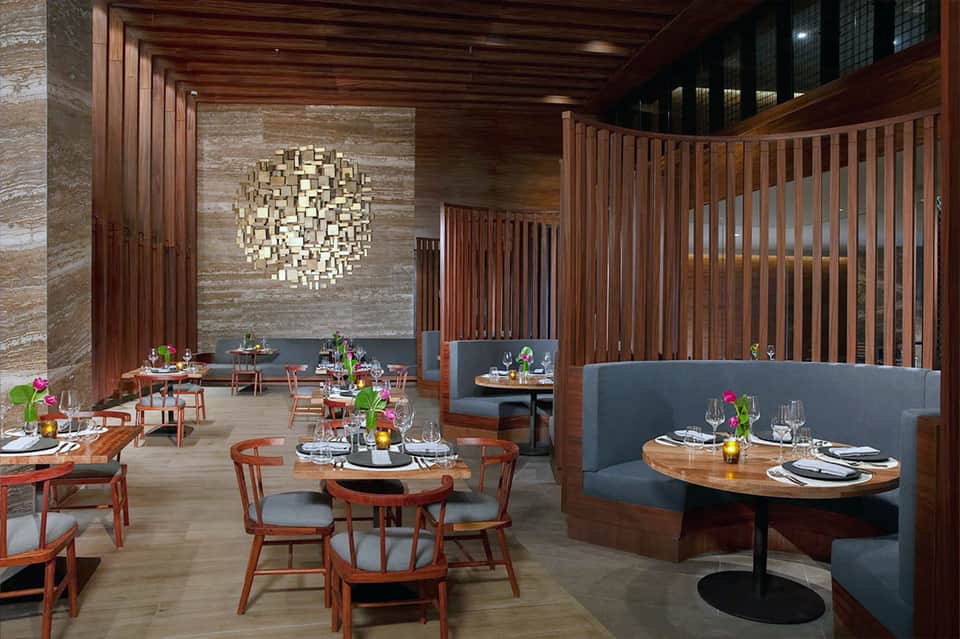Upscale restaurant interior with wooden accents, banquettes, and artful ceiling fixture