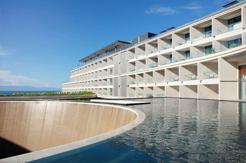 Contemporary white resort building with curved pool and sea view
